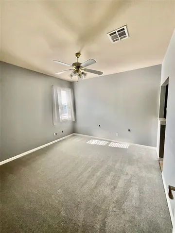 an empty room with chandelier fan and windows