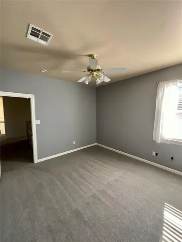 an empty room with windows and fan