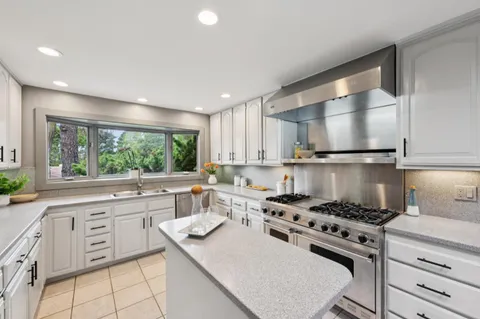 a kitchen with stainless steel appliances white cabinets and a large window