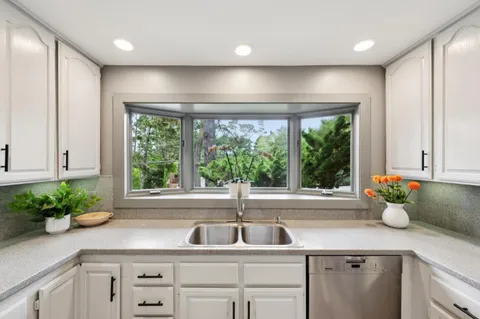 a kitchen that has a lot of white cabinets and stainless steel appliances