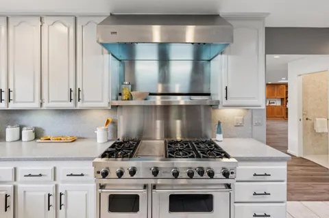 a kitchen with a dining table chairs stove microwave and cabinets