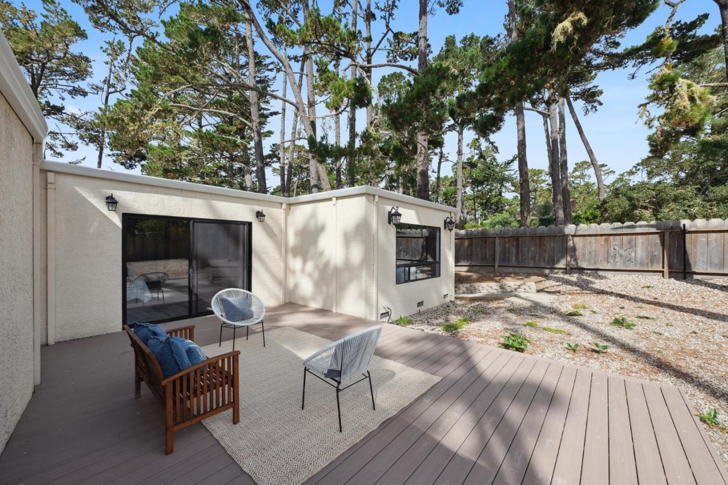 4083 Sunset Lane Pebble Beach, CA 93953 - Photo 31 of 54 a backyard of a house with table and chairs wooden floor and a barbeque with potted plants and large trees
