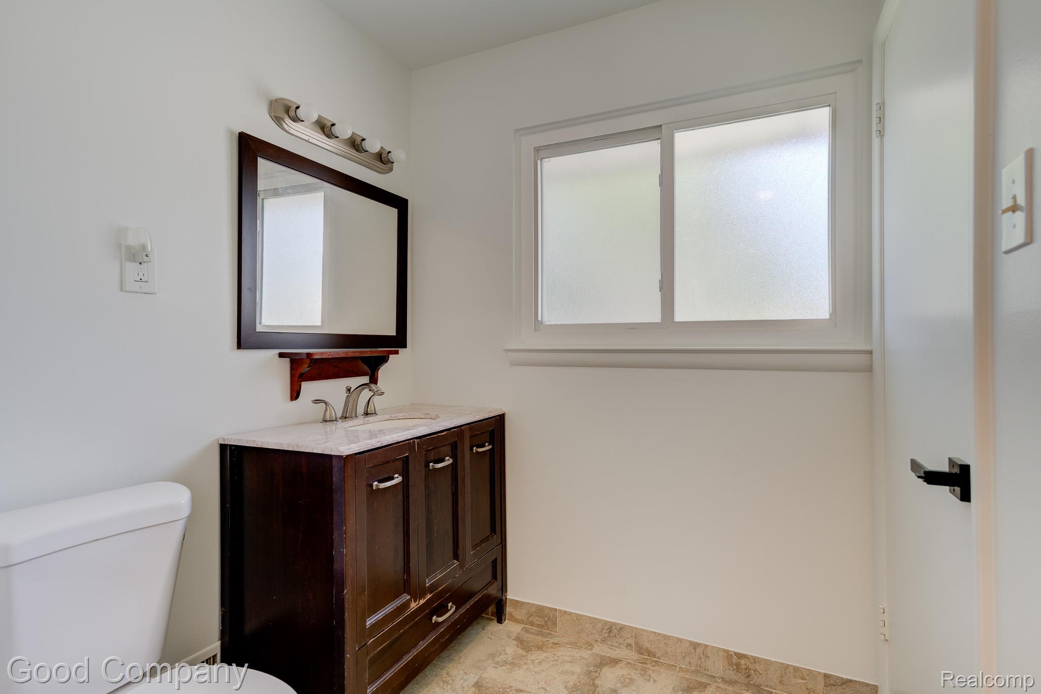 1842 Massoit Road Royal Oak, MI 48073 - Photo 26 of 52 White walls with a dark wood-finish vanity and mirror, featuring a light countertop and tile flooring
