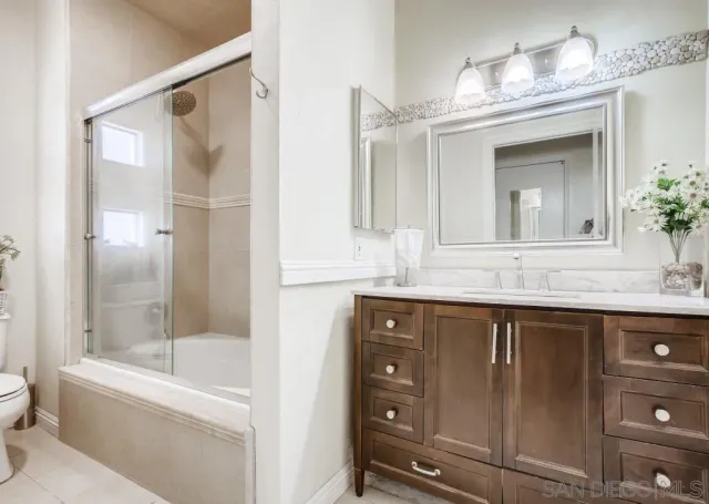 a bathroom with a granite countertop sink mirror toilet and bathtub