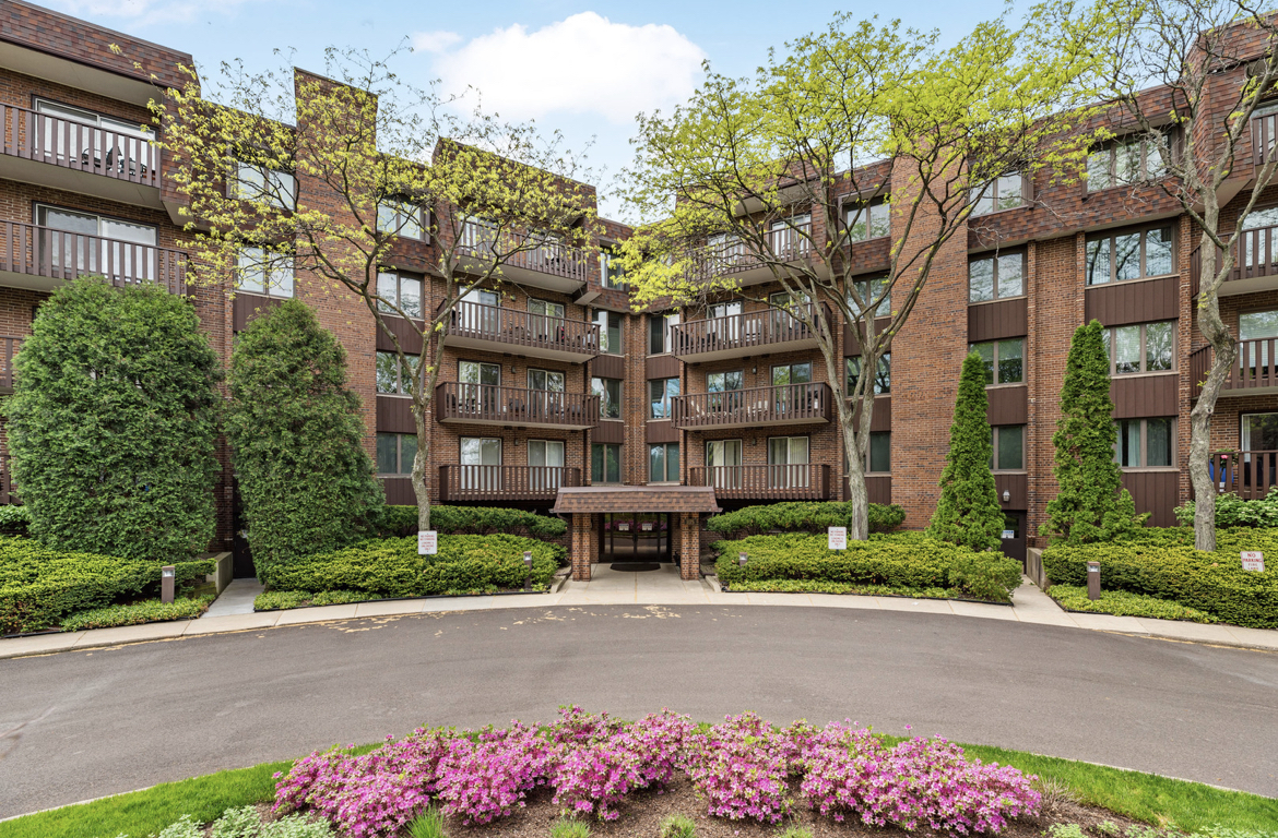 a front view of multi story residential apartment building with yard and sign board