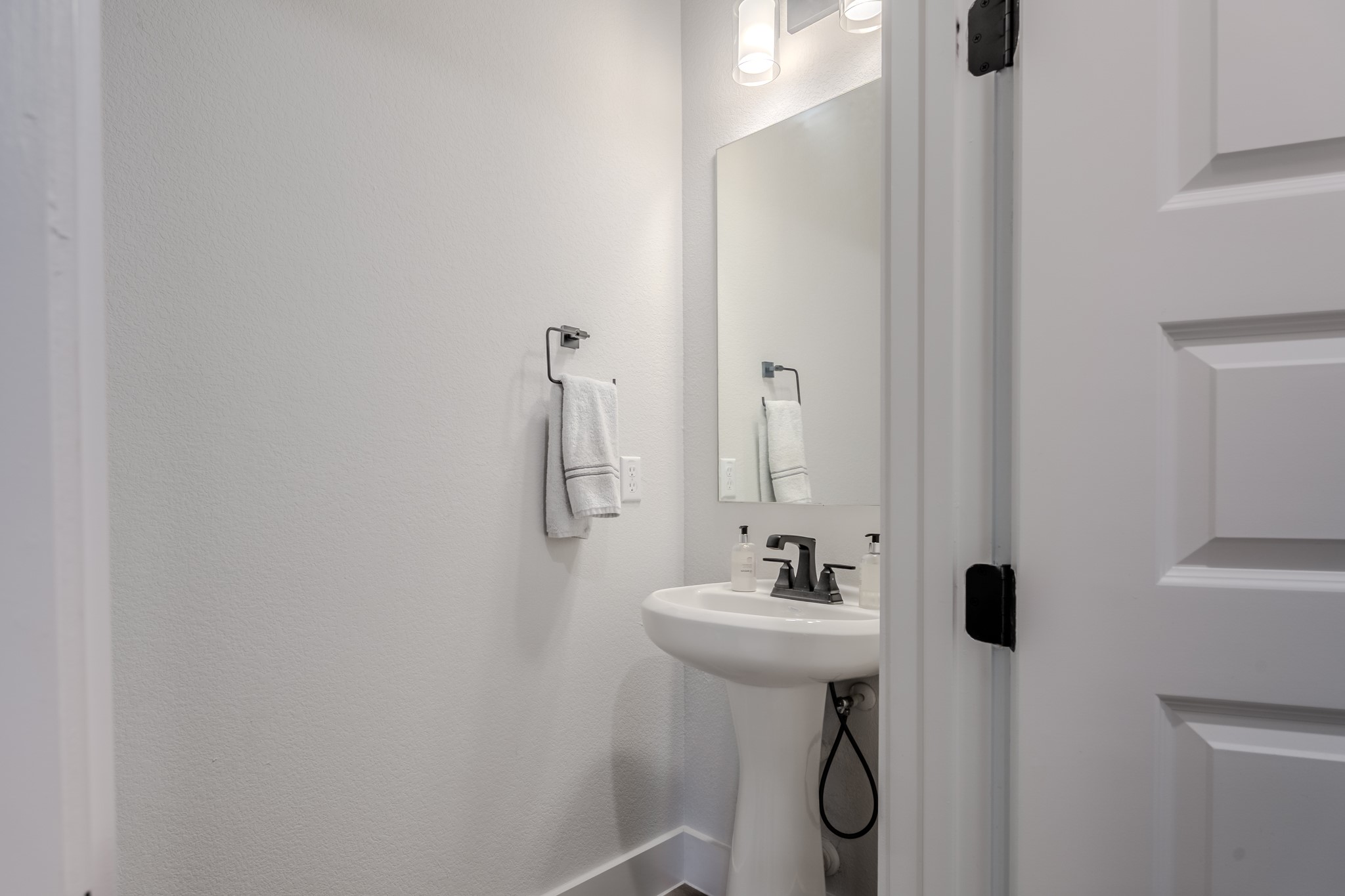 8109 Edmondson Bend Austin, TX 78744 - Photo 6 of 38 A well-lit powder room featuring a classic pedestal sink and clean, simple finishes.