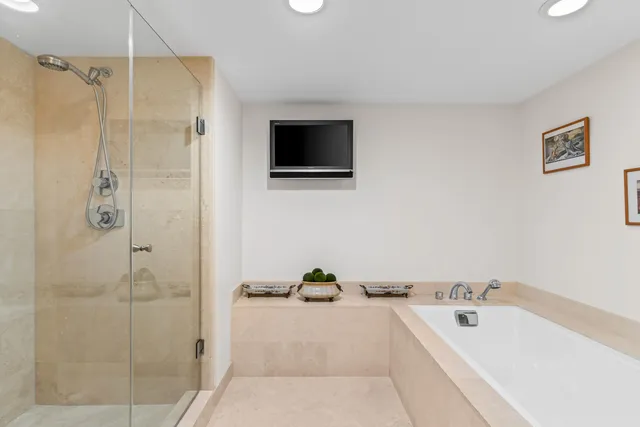 a spacious bathroom with a tub a mirror and a shower