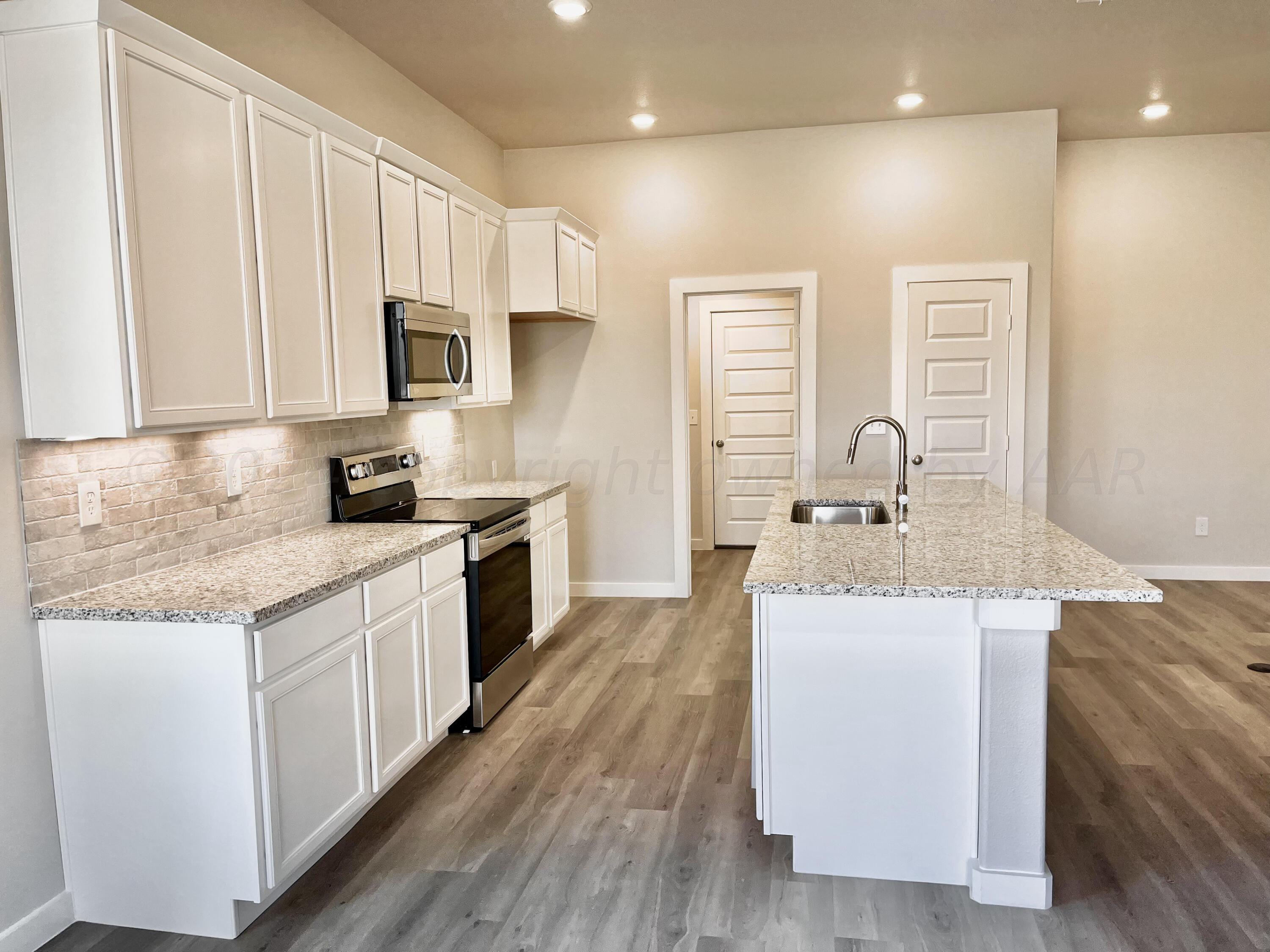 7515 Frazier Road Amarillo, TX 79119 - Photo 8 of 23 a kitchen with kitchen island granite countertop a sink and wooden cabinets