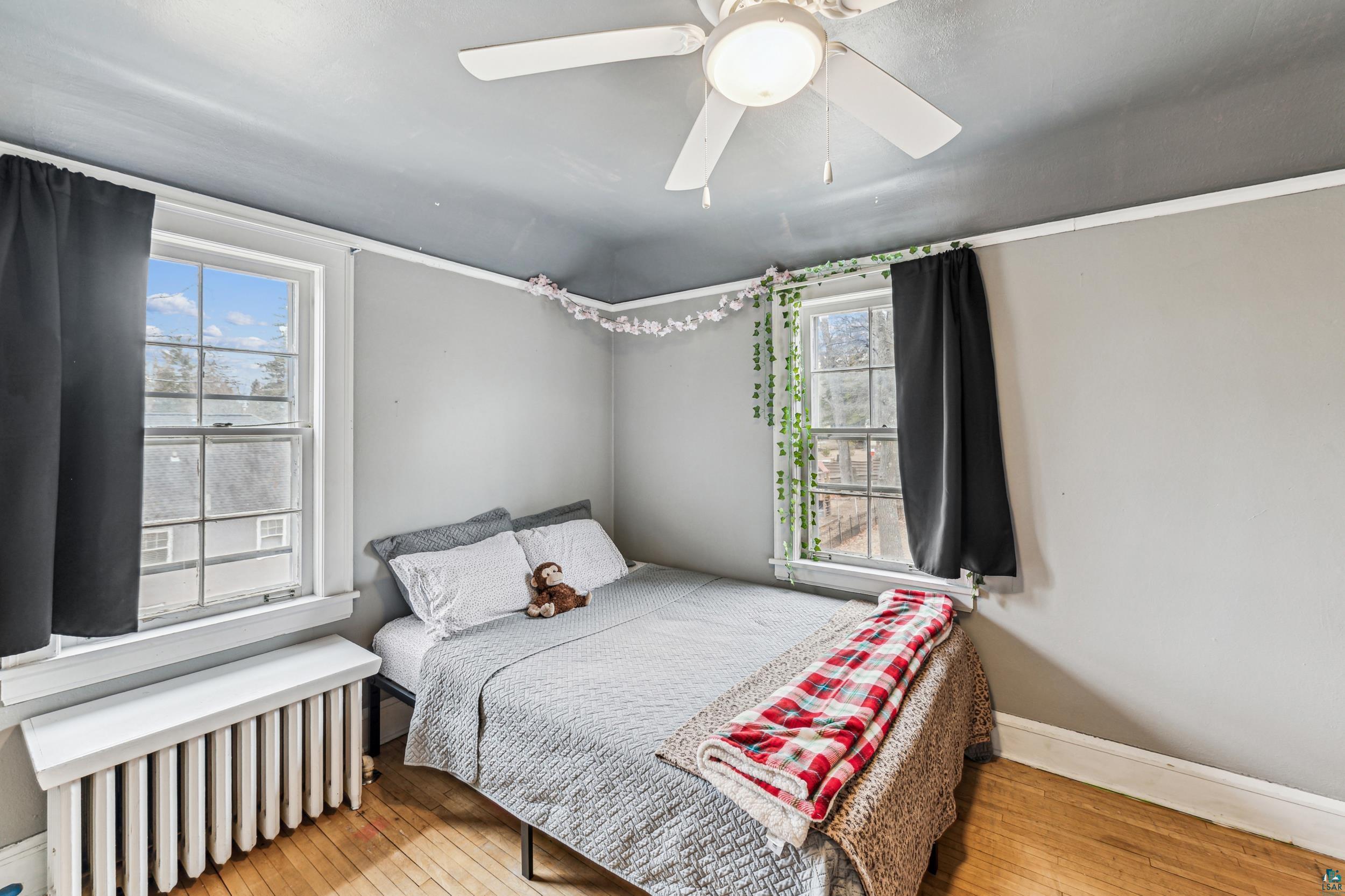 2111 Lakeview Drive Duluth, MN 55803 - Photo 15 of 21 Bedroom featuring baseboards, wood-type flooring, radiator, and a ceiling fan