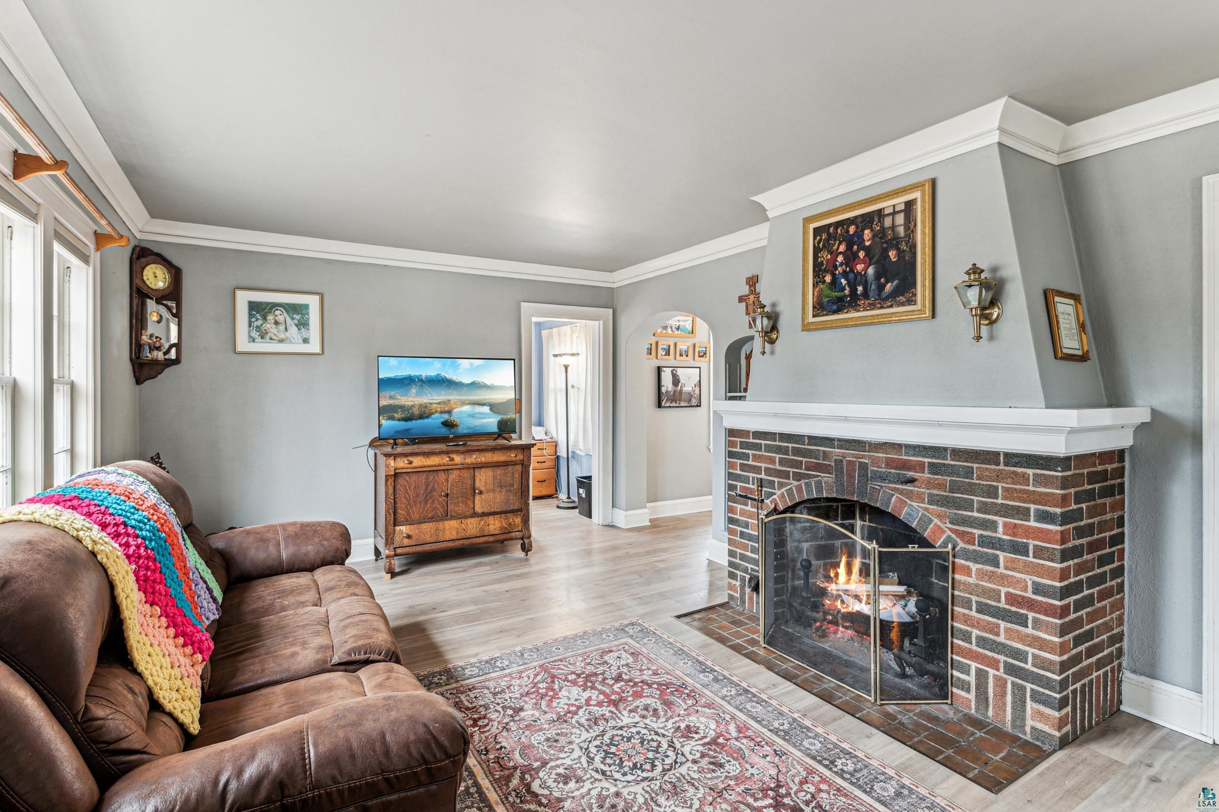 2111 Lakeview Drive Duluth, MN 55803 - Photo 4 of 21 Living area with a brick fireplace, baseboards, light wood-style floors, and ornamental molding