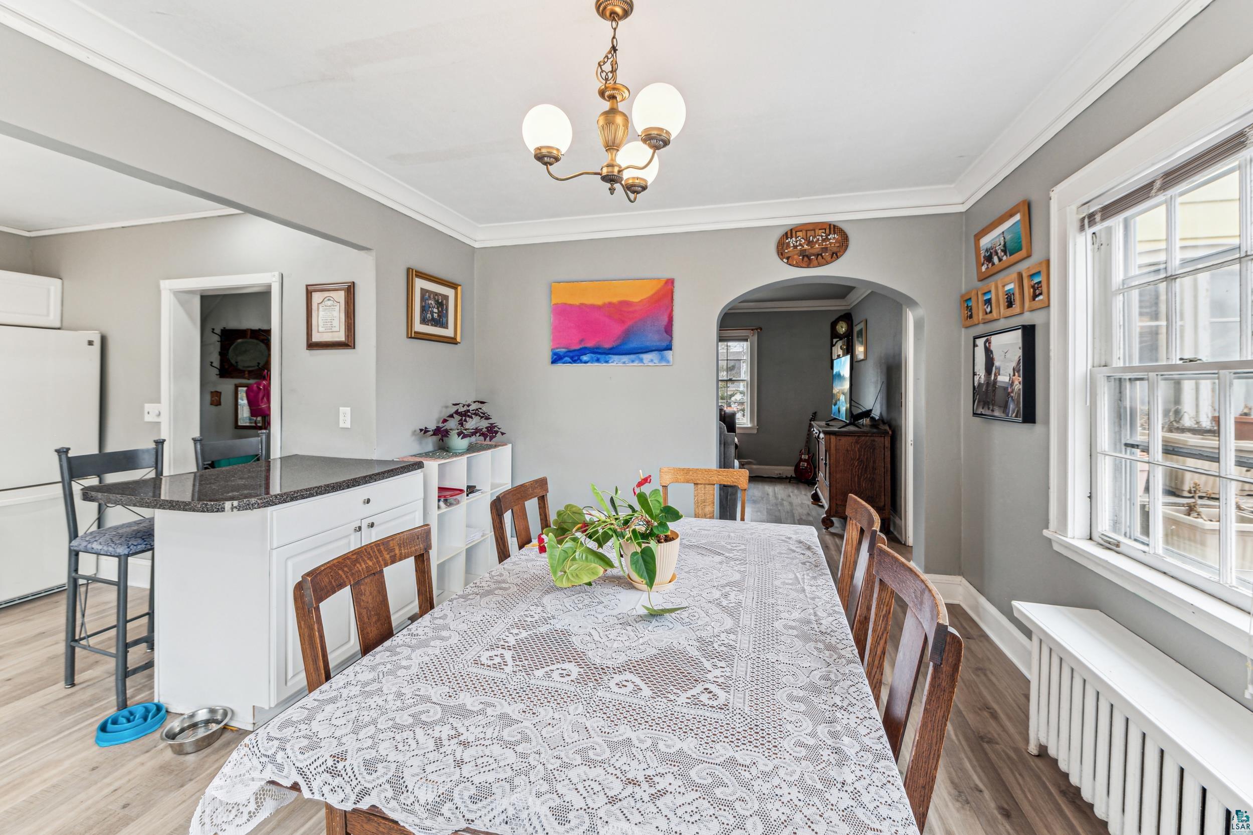 2111 Lakeview Drive Duluth, MN 55803 - Photo 7 of 21 Dining area featuring light wood-type flooring, arched walkways, radiator heating unit, and crown molding