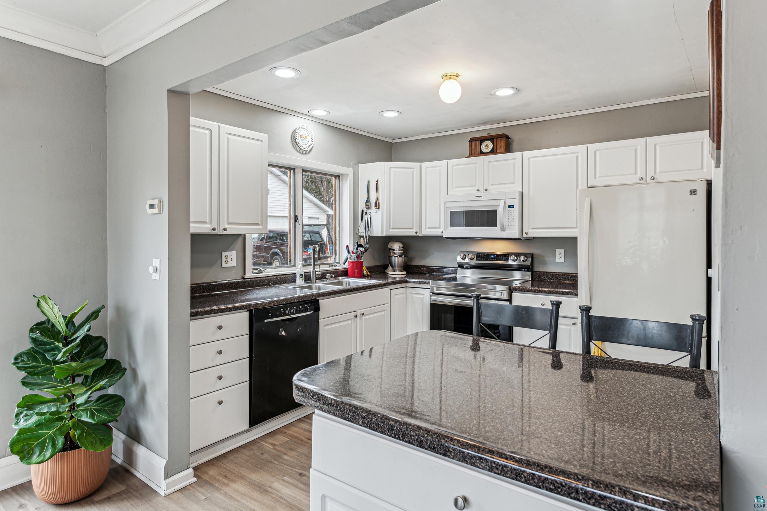 2111 Lakeview Drive Duluth, MN 55803 - Photo 8 of 21 Kitchen with dark countertops, light wood-type flooring, ornamental molding, white appliances, and a sink