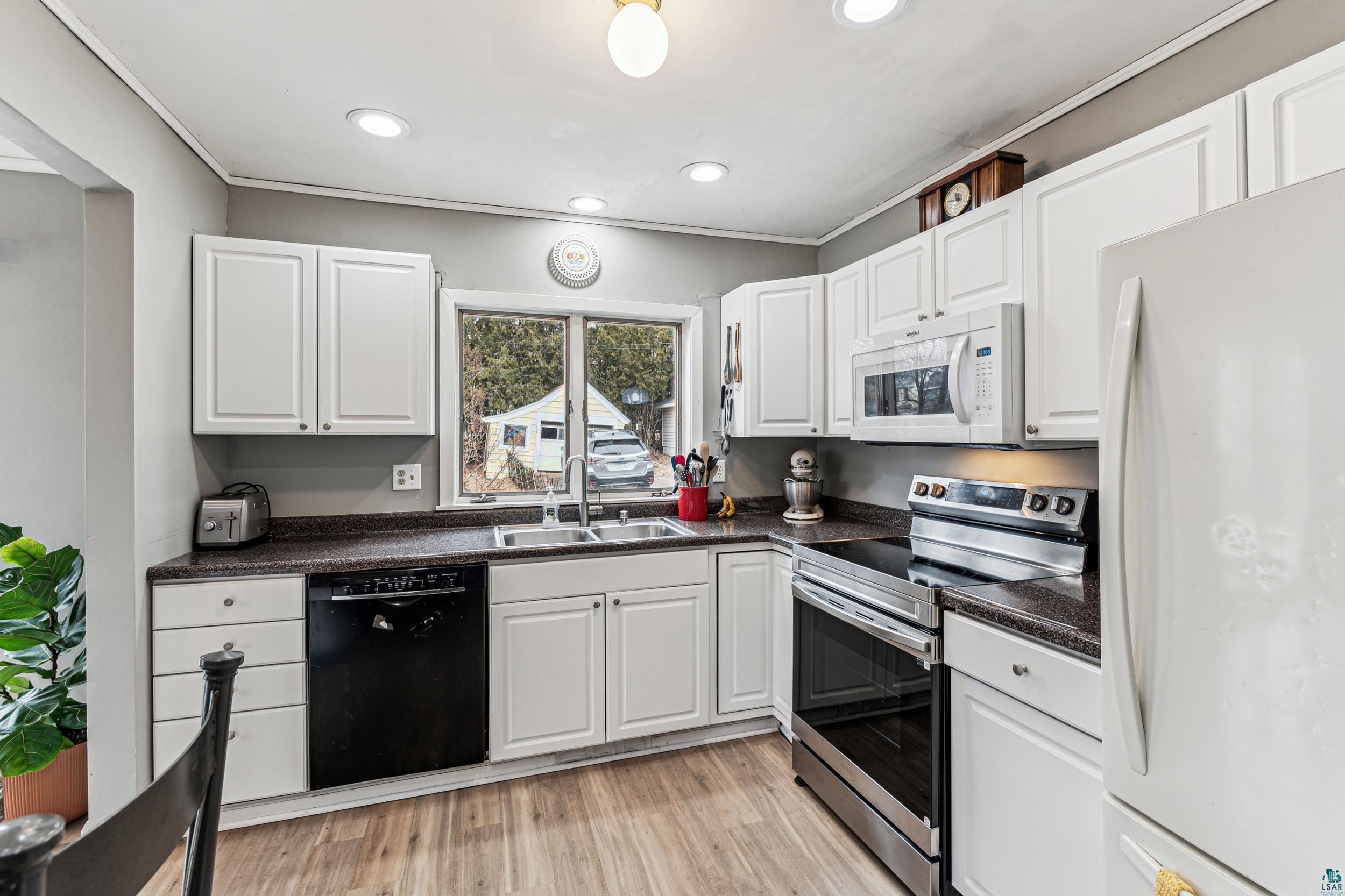 2111 Lakeview Drive Duluth, MN 55803 - Photo 10 of 21 Kitchen featuring white appliances, a sink, white cabinets, light wood-style floors, and dark countertops
