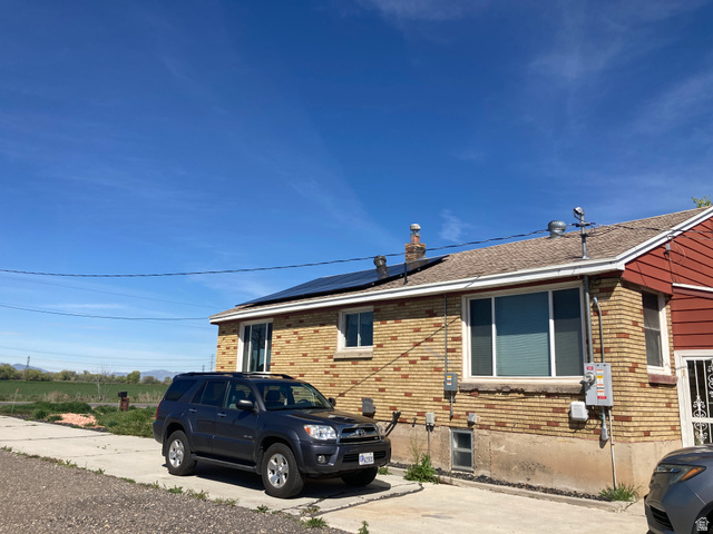 200 South 2800th Street West Ogden, UT 84404 - Photo 34 of 42 View of home's exterior featuring brick siding, roof mounted solar panels, and a shingled roof