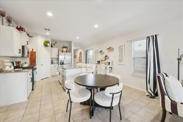 a living room with stainless steel appliances furniture a rug and a kitchen view