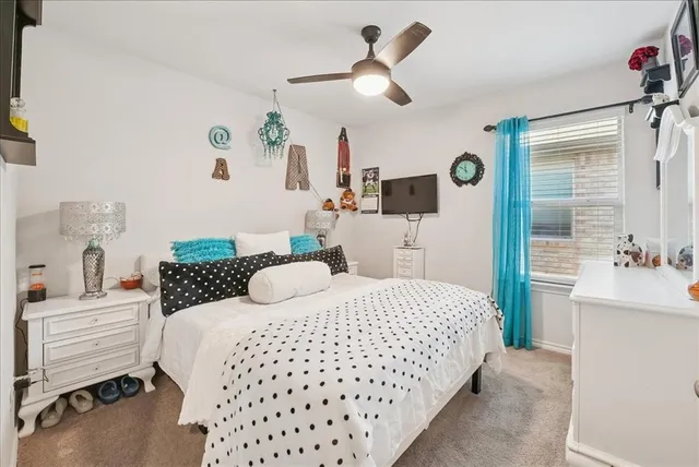 a bedroom with a bed a dresser and potted plant