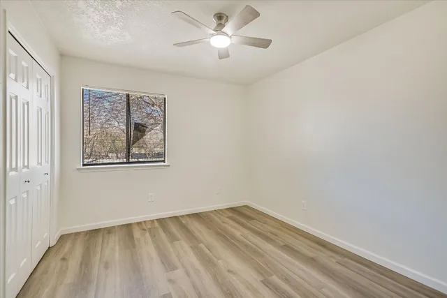 a view of empty room with wooden floor and fan