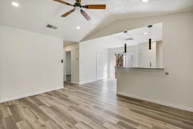 a view of a hallway with wooden floor and a ceiling fan