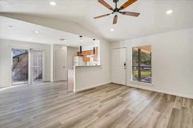 a view of an empty room with window and wooden floor