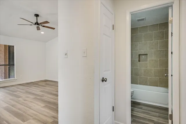 a view of empty room with wooden floor and fan