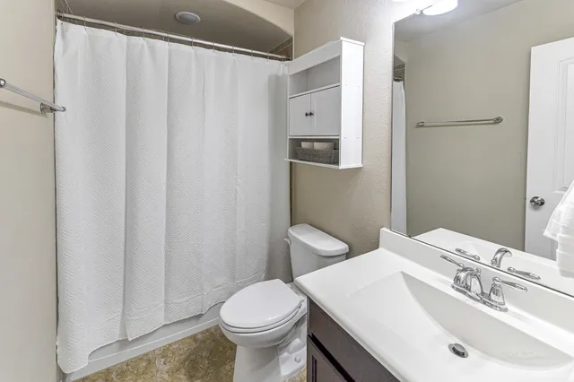 a bathroom with a sink a toilet and shower curtain