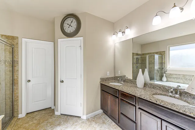 a bathroom with a granite countertop double vanity sink and a mirror