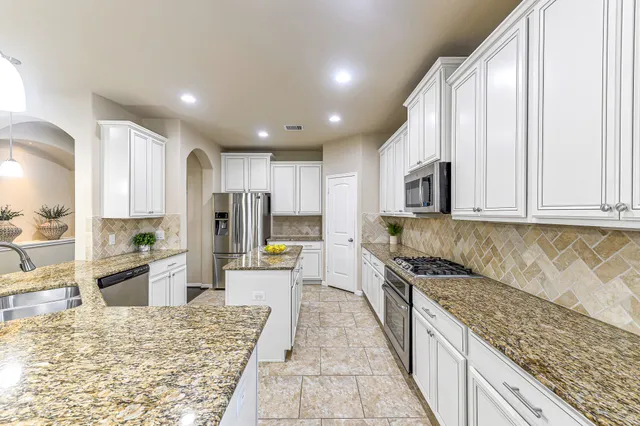 a large kitchen with kitchen island granite countertop a large counter top stainless steel appliances and cabinets