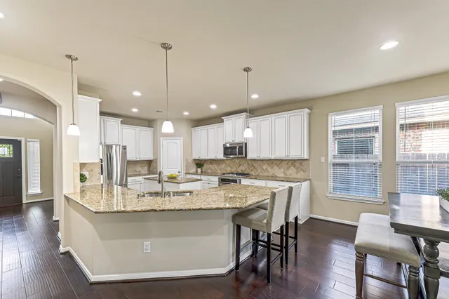 a large kitchen with a dining table chairs wooden floor and appliances