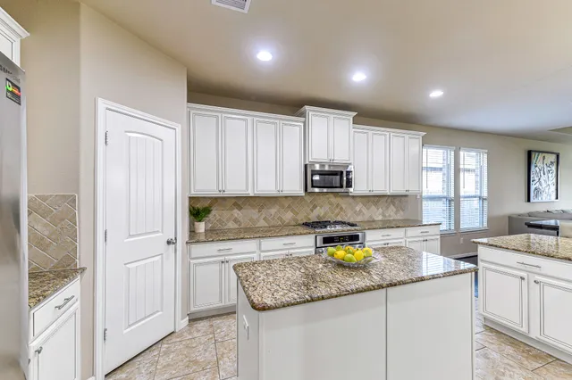 a kitchen with kitchen island granite countertop a sink a stove cabinets and counter space