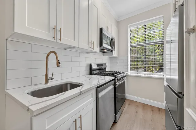 a kitchen with stainless steel appliances granite countertop a sink stove and white cabinets
