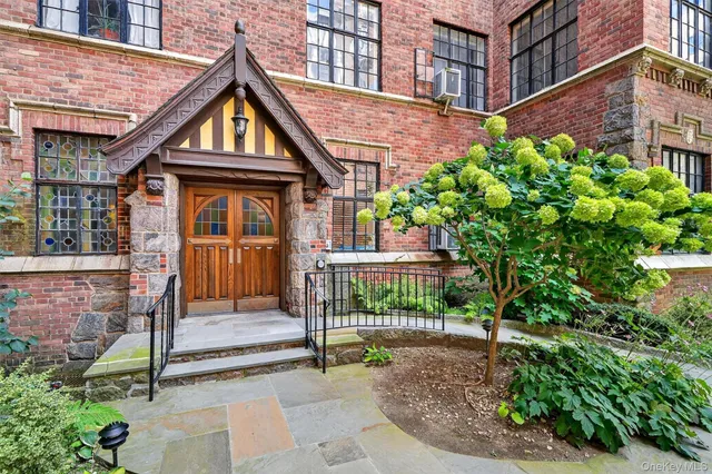 a view of a brick house with large windows and plants