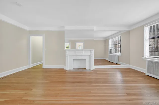 a view of an empty room with window and wooden floor