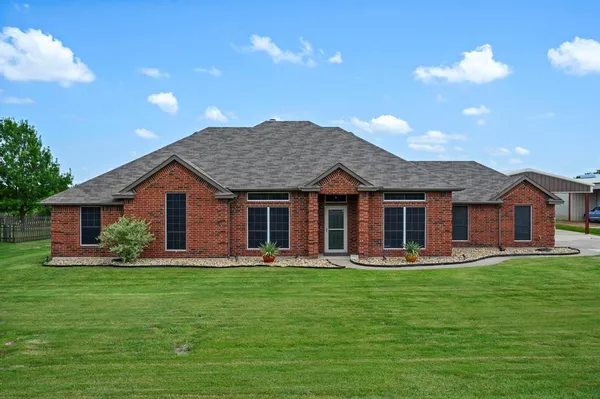 a front view of a house with a garden and trees