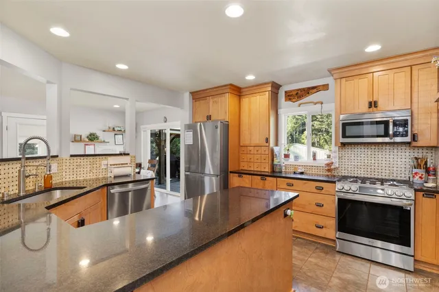 a kitchen with stainless steel appliances granite countertop a sink and a refrigerator