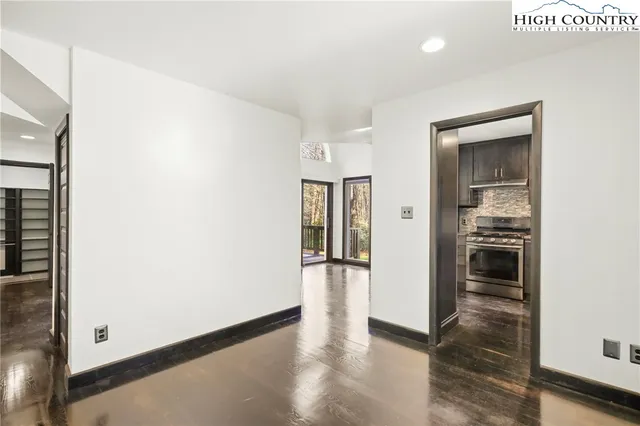 a view of an empty room with wooden floor and a ceiling fan