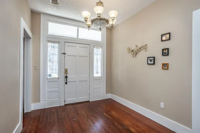 a view of a hallway with wooden floor and a chandelier