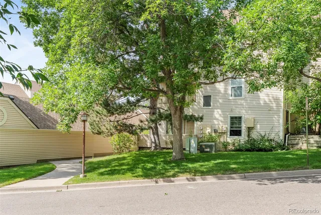 a front view of a house with a garden and tree