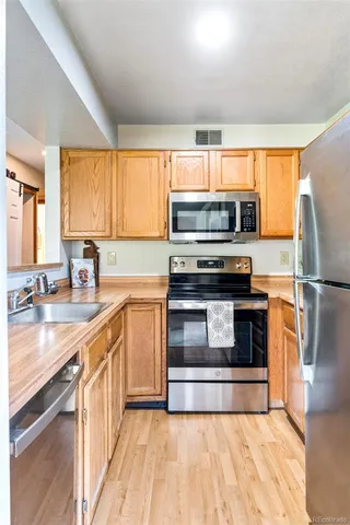 a kitchen with kitchen island granite countertop a sink cabinets and stainless steel appliances