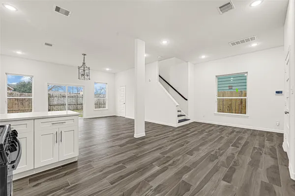 a view of an empty room with wooden floor and windows