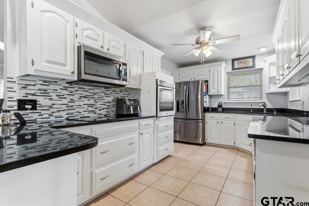 1302 Lake Cross Road Hideaway, TX 75771 - Photo 16 of 31 a kitchen with granite countertop a sink stainless steel appliances and white cabinets