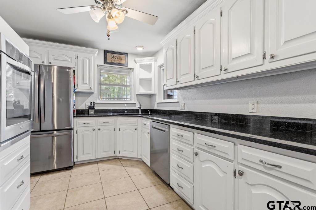 1302 Lake Cross Road Hideaway, TX 75771 - Photo 17 of 31 a kitchen with granite countertop white cabinets stainless steel appliances and sink