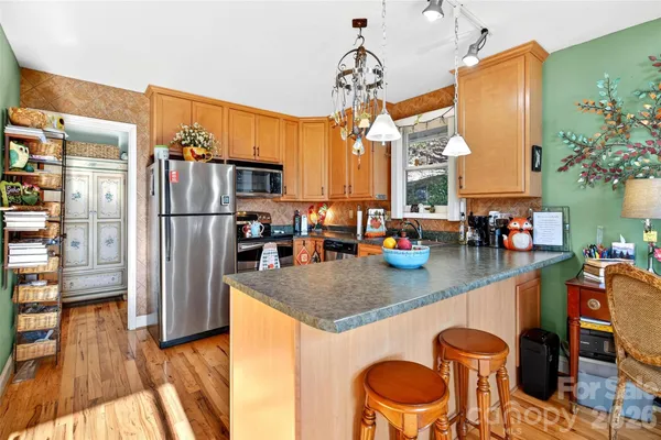 a kitchen with stainless steel appliances granite countertop a table chairs in it and wooden floors