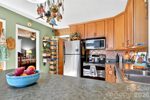 a kitchen with stainless steel appliances granite countertop a sink dishwasher and a refrigerator with wooden floor