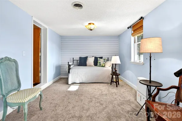 a bedroom with a bed a couch and a lamp next to a window