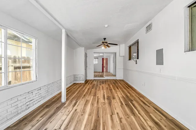 a view of an empty room with wooden floor and a window