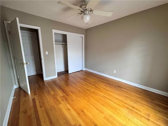 an empty room with wooden floor chandelier fan and windows