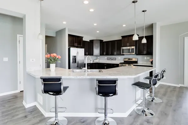 a kitchen with stainless steel appliances kitchen island granite countertop a dining table chairs and white cabinets