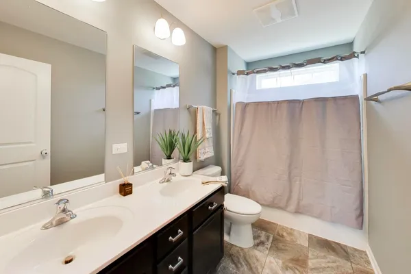 a bathroom with a sink toilet double vanity and shower
