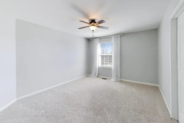 an empty room with a ceiling fan and window