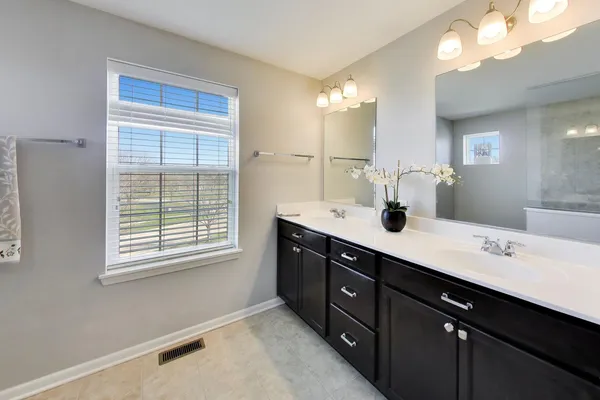a spacious bathroom with a double vanity sink a mirror a and a window